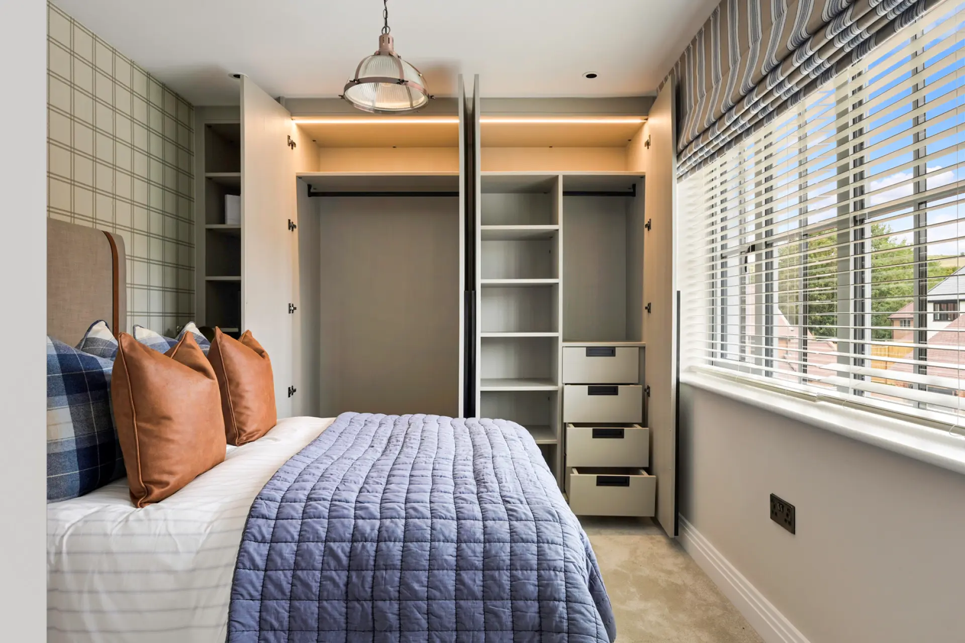 a bed with a blue blanket and brown pillows in a room with a closet